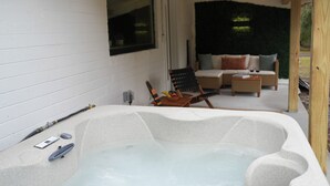 A spa area with a hot tub, wooden deck, and outdoor seating.