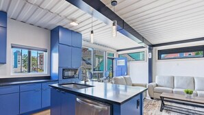 A modern kitchen with blue cabinets, a central island, and pendant lighting. - Location Location Location! New Indy Custom Home (Indianapolis)