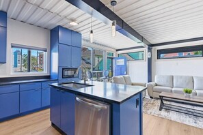 A modern kitchen with blue cabinets, a central island, and pendant lighting.