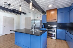 A modern kitchen with blue cabinets, stainless steel appliances, and pendant lighting. - Location Location Location! New Indy Custom Home (Indianapolis)