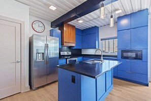 A modern kitchen with blue cabinets, stainless steel appliances, and a central island.