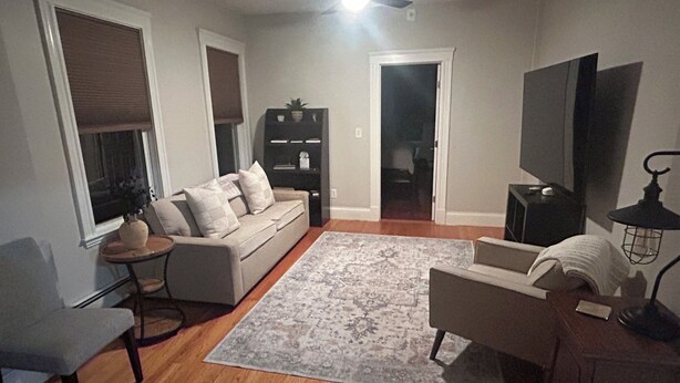 A living room with a sofa, a coffee table, a TV, and a bookshelf. - Harvard, B.U. M.I.T. Fenway Park convenient comfortable & spacious 3BR apartment (Cambridge)