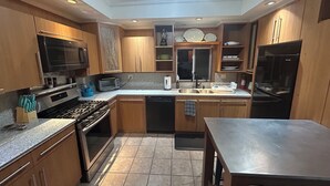A modern kitchen with wooden cabinets, stainless steel appliances, and a tiled floor. - Harvard, B.U. M.I.T. Fenway Park convenient comfortable & spacious 3BR apartment (Cambridge)