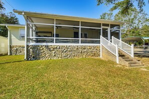 A two-story house with a stone foundation, a covered porch with a staircase, and a clear blue sky. - Walk to Marina! Prosperity Home w/ Screened Porch (Prosperity)
