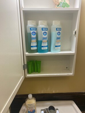 Une étagère de salle de bain avec trois flacons de gel douche White Rain, deux flacons d’après-shampoing White Rain et trois tubes de shampoing verts.
