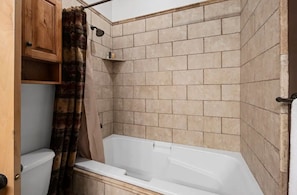 A bathroom with a bathtub, a shower, and a toilet. There is a wooden cabinet and a shelf with toiletries. - Timberline Condo at Moose Hollow, end unit w/ full windows, steps from hot tub  (Eden)
