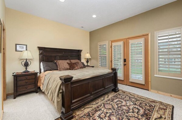A bedroom with a large bed, two bedside tables with lamps, a patterned rug, and a view through the door. - Timberline Condo at Moose Hollow, end unit w/ full windows, steps from hot tub  (Eden)