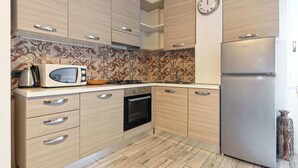 A kitchen with wooden cabinets, a microwave, a stove, and a refrigerator.