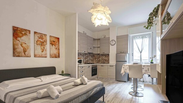 A modern bedroom with a bed, a dining area, and a kitchen.