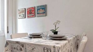 A dining table with a patterned tablecloth, plates, a glass, and a potted orchid.