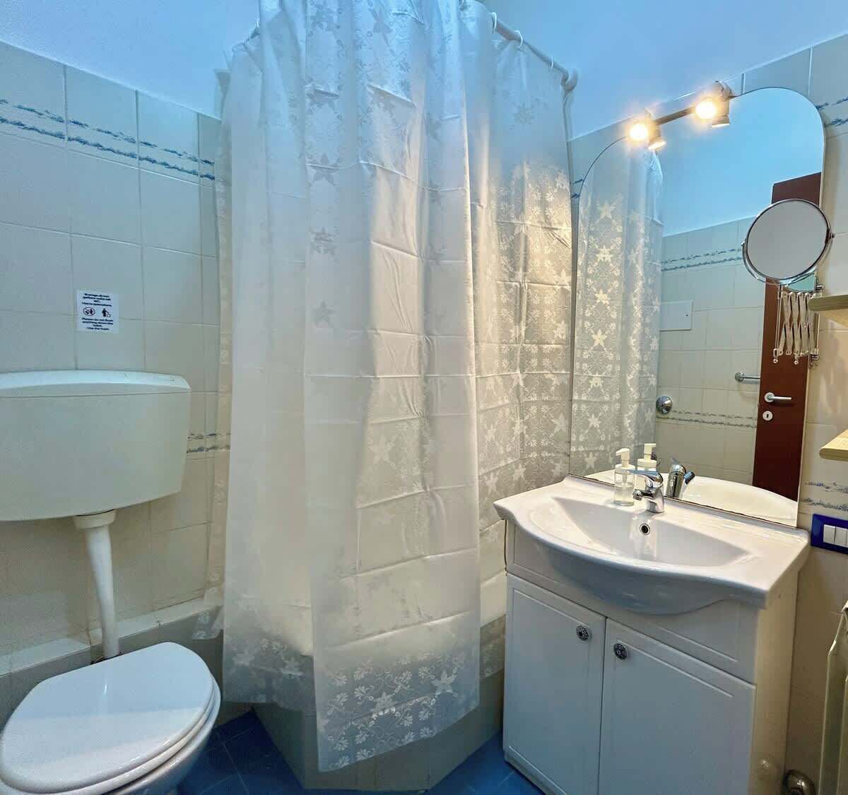 Un baño con inodoro, lavamanos y cortina de ducha.