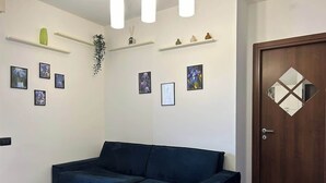 A room with a dark blue sofa, white walls, and a wooden door with a diamond-shaped mirror.