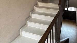 A staircase with a wooden handrail leading to a landing.