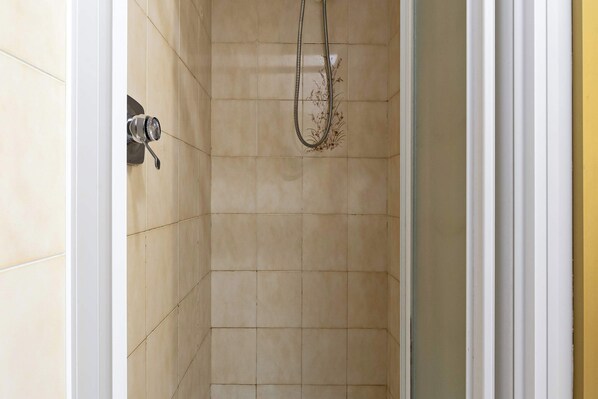 A shower with beige tiles and a handheld showerhead.