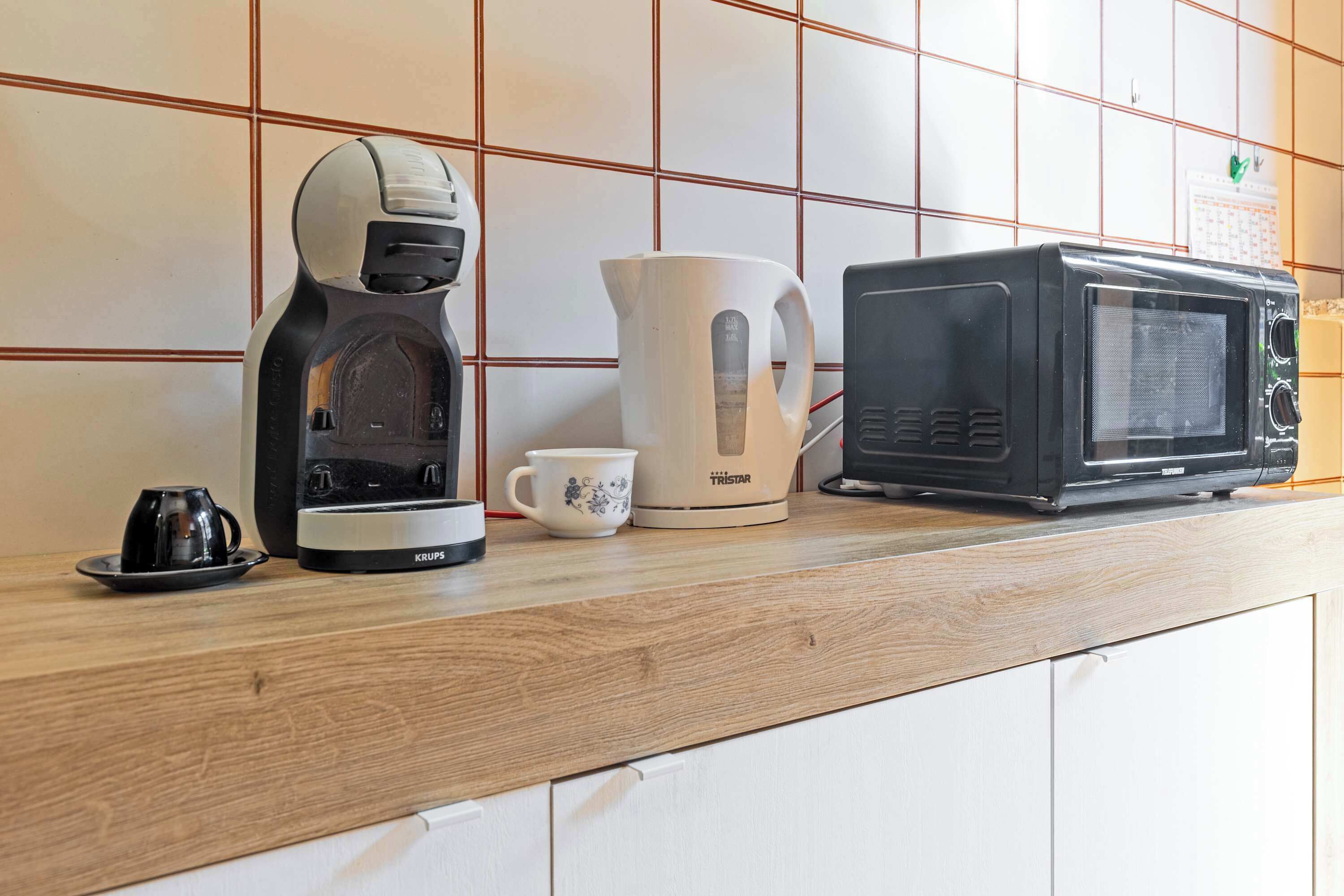 Un plan de travail de cuisine avec une machine à café, une bouilloire et un four à micro-ondes.