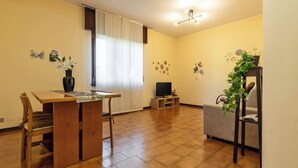Ein Wohnzimmer mit einem Holzesstisch, einer Couch, einem Fernseher und einer Pflanze.
