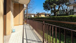 Ein Wohngebäude mit Balkon, einem Pflasterweg und einer Hecke.