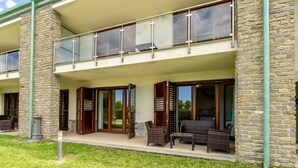 A two-story building with a balcony, stone pillars, and a grassy area with outdoor furniture. - Chianti Village Studio Apartment (Barberino Tavernelle)