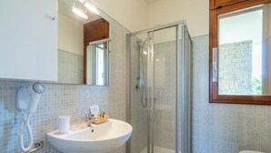 A bathroom with a glass-enclosed shower, a white sink, and a mirror above it. - Chianti Village Studio Apartment (Barberino Tavernelle)
