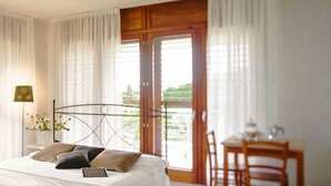 A bedroom with a bed, a bedside table, a chair, and a view of the outdoors. - Chianti Village Studio Apartment (Barberino Tavernelle)