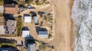 Oversigtsbillede af et kystområde med bygninger, en strand og havnebølger.