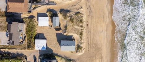 An aerial view of a coastal area with buildings, a beach, and ocean waves.
