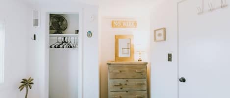 A bedroom with a bed, a dresser, a closet, and a 'NO WAKE' sign.