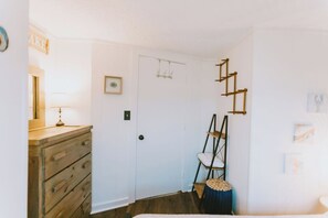 A room with a wooden dresser, a white door, and a wall-mounted ladder. - Coastal Dunes 1: Oceanfront Cottage in Nags Head, Great Views! (Nags Head)