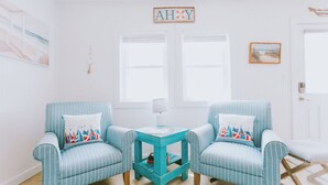 A room with two striped armchairs, a small teal side table, and a wall-mounted sign reading "AHOY". - Coastal Dunes 2: Pet Friendly, Oceanfront Cottage in Nags Head (Nags Head)