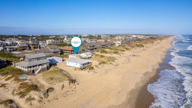 A coastal residential area with beachfront properties, including houses and a beach house with a porch. - Coastal Dunes 2: Pet Friendly, Oceanfront Cottage in Nags Head (Nags Head)