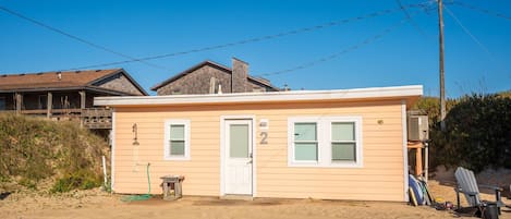 Einbungalow am Strand mit weißer Tür, Nummer 2, und einer kleinen Veranda.