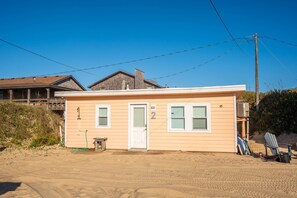 A single-story beach house with a white door, numbered "2", and a small porch area. - Coastal Dunes 2: Pet Friendly, Oceanfront Cottage in Nags Head (Nags Head)