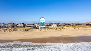 A coastal beach view with houses and a location marker.