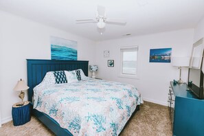 Une chambre à coucher avec un lit, un ventilateur de plafond, une fenêtre et une commode.