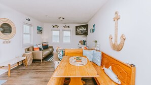 A cozy, nautical-themed living room with a wooden dining table, a bench, and a sofa.