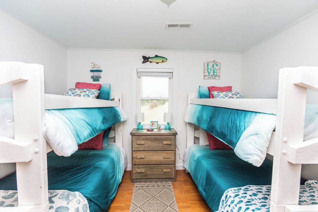 A room with bunk beds, a dresser, and a window.