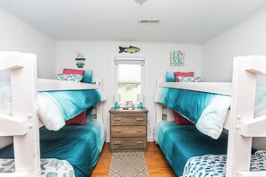 Une chambre avec des lits superposés, une commode et une fenêtre.