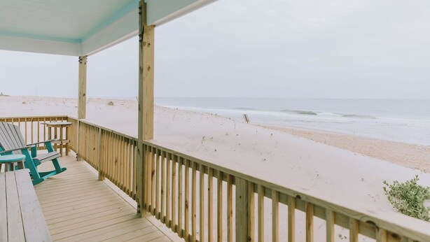 A wooden deck with a view of the beach and ocean.