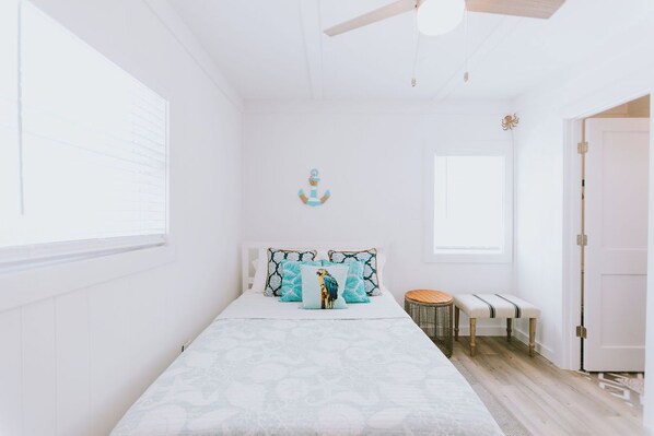 Une chambre à coucher avec un lit, un ventilateur de plafond, une petite table ronde et un banc.