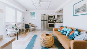 Un espacio habitable compacto con kitchenette, zona de comedor y sala de estar con sofá y sillas.