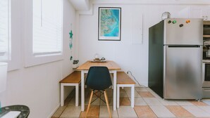 Una cocina compacta con una mesa de madera, una silla negra y un refrigerador de acero inoxidable.
