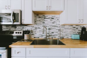 A modern kitchen with white cabinets, a stainless steel sink, a microwave, and a toaster. - Coastal Dune 4: Pet-Friendly, Cottage on the Beach in Nags Head (Nags Head)