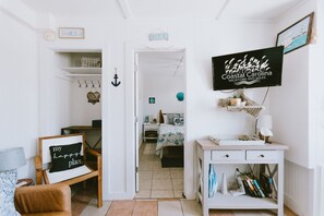 A cozy room with a bed, a desk, and a TV displaying 'Coastal Carolina Vacations and Sales'. - Coastal Dune 4: Pet-Friendly, Cottage on the Beach in Nags Head (Nags Head)