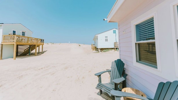 Een strandhuis met een terras en een klein portaal, gelegen aan een zandstrand.