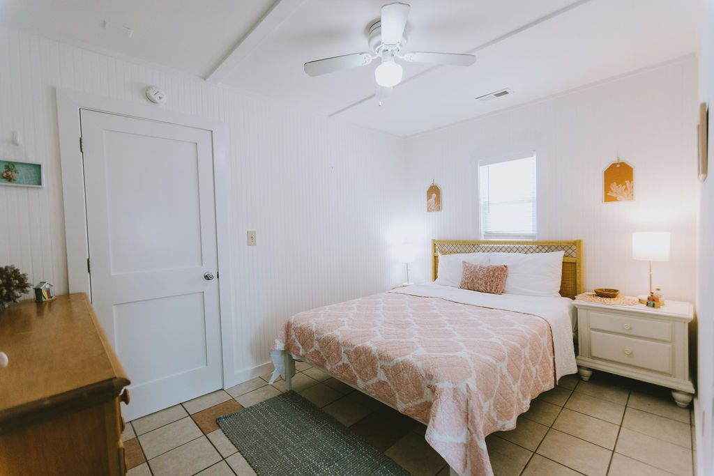 Un dormitorio con cama, mesita de noche y ventilador de techo.