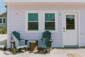 A house with two green Adirondack chairs and a small table outside.