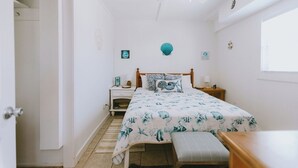 Un dormitorio con cama, mesitas de noche, ventilador de techo y ventana.