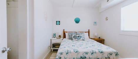 A bedroom with a bed, bedside tables, a ceiling fan, and a window.