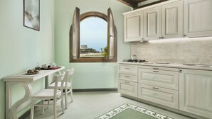 A kitchen with white cabinets, a dining table with chairs, a window with an open arch, and a view of the outside. - Nice apartment on the ground floor with sea view of about 45 m2 equipped with air conditioning and wi fi connection, composed of a living room with equipped kitchenette, fridge and flat-screen television.It can be on one level or with a mezzanineA double (Bosa Marina)