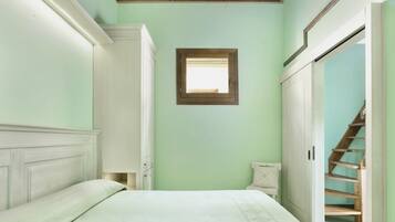A bedroom with a bed, a window, and a staircase.